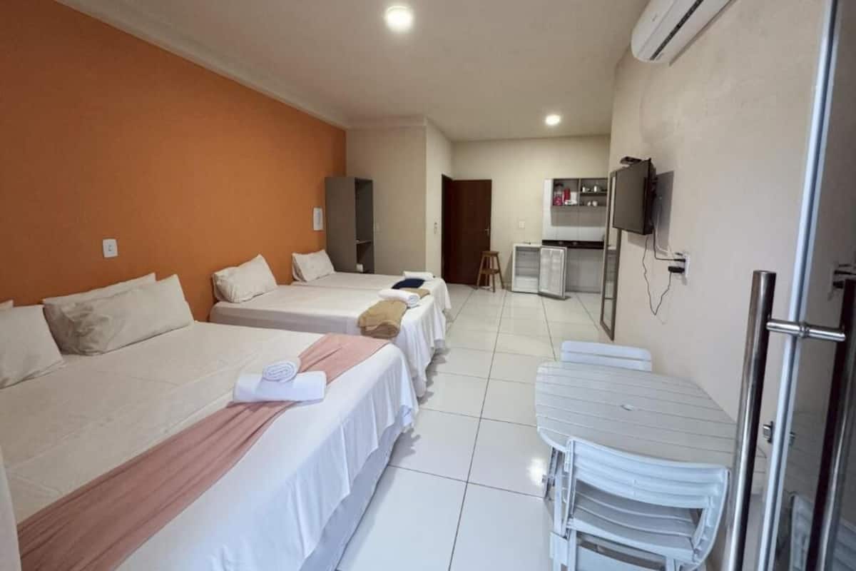Habitación de hotel con dos camas, kitchenette y televisión.