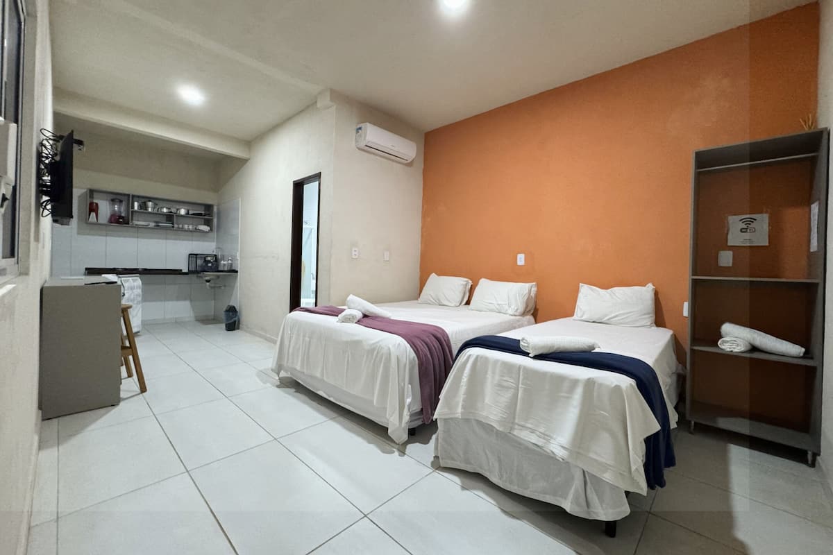 Una habitación de hotel con dos camas, kitchenette y baño.