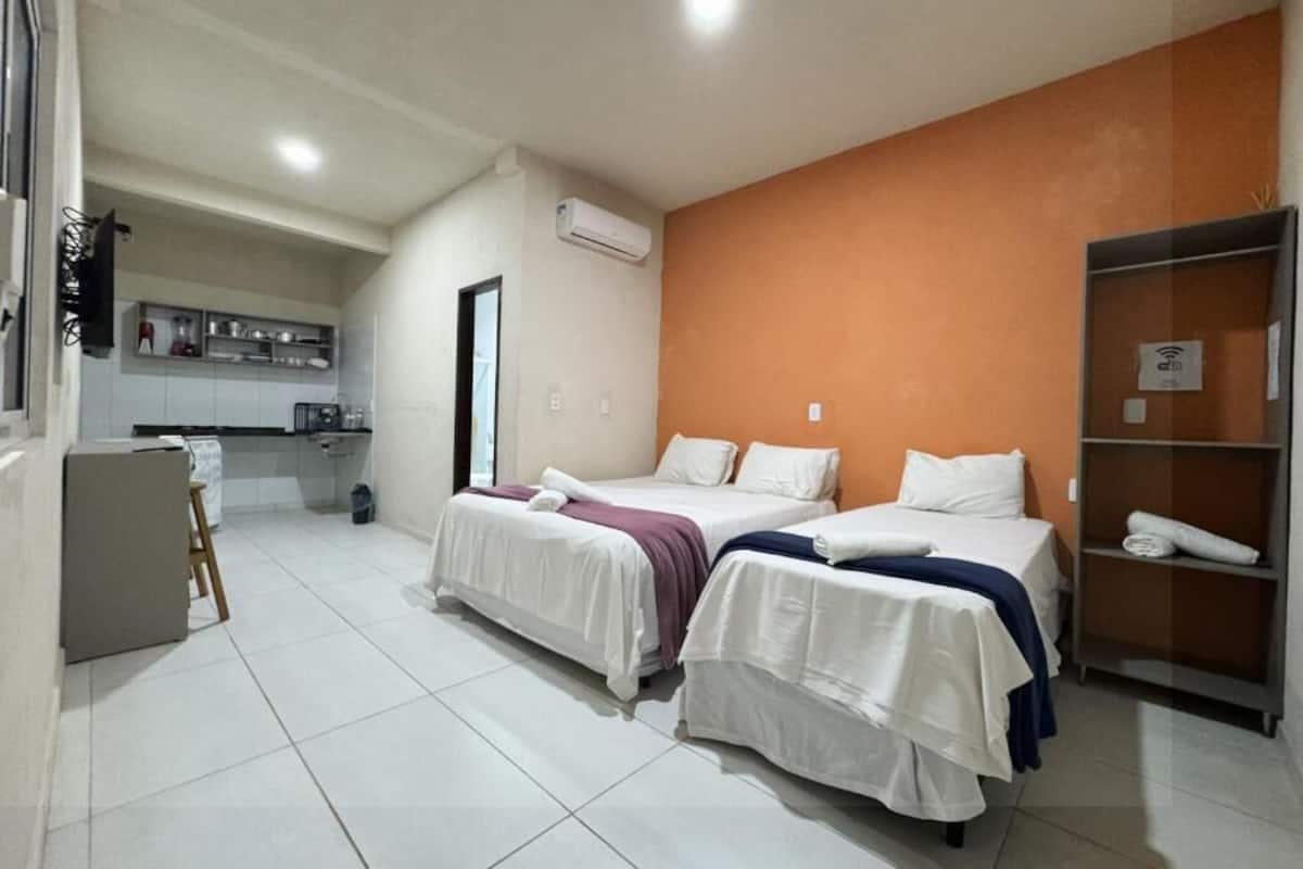 Una habitación con dos camas, kitchenette y baño.