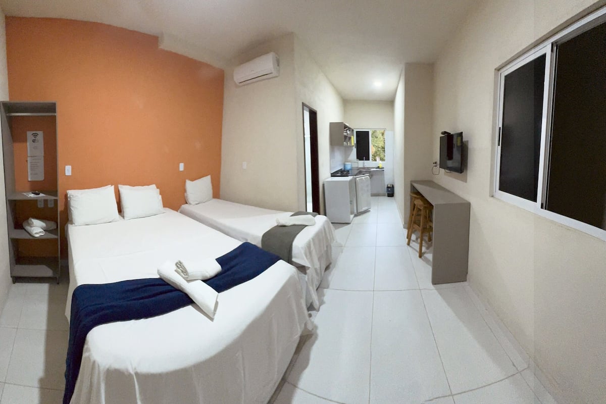 Una habitación de hotel con dos camas, kitchenette, televisión y baño.