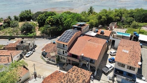 Zona residencial costera con edificios de techos rojos, paneles solares y vistas al mar.