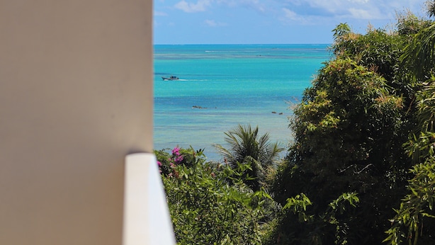 Vista de una playa tropical con aguas turquesas cristalinas, un bote y abundante vegetación.