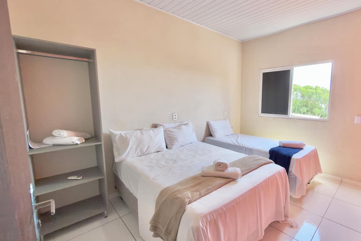 Un dormitorio con cama, dos mesitas de noche, un armario y una ventana.