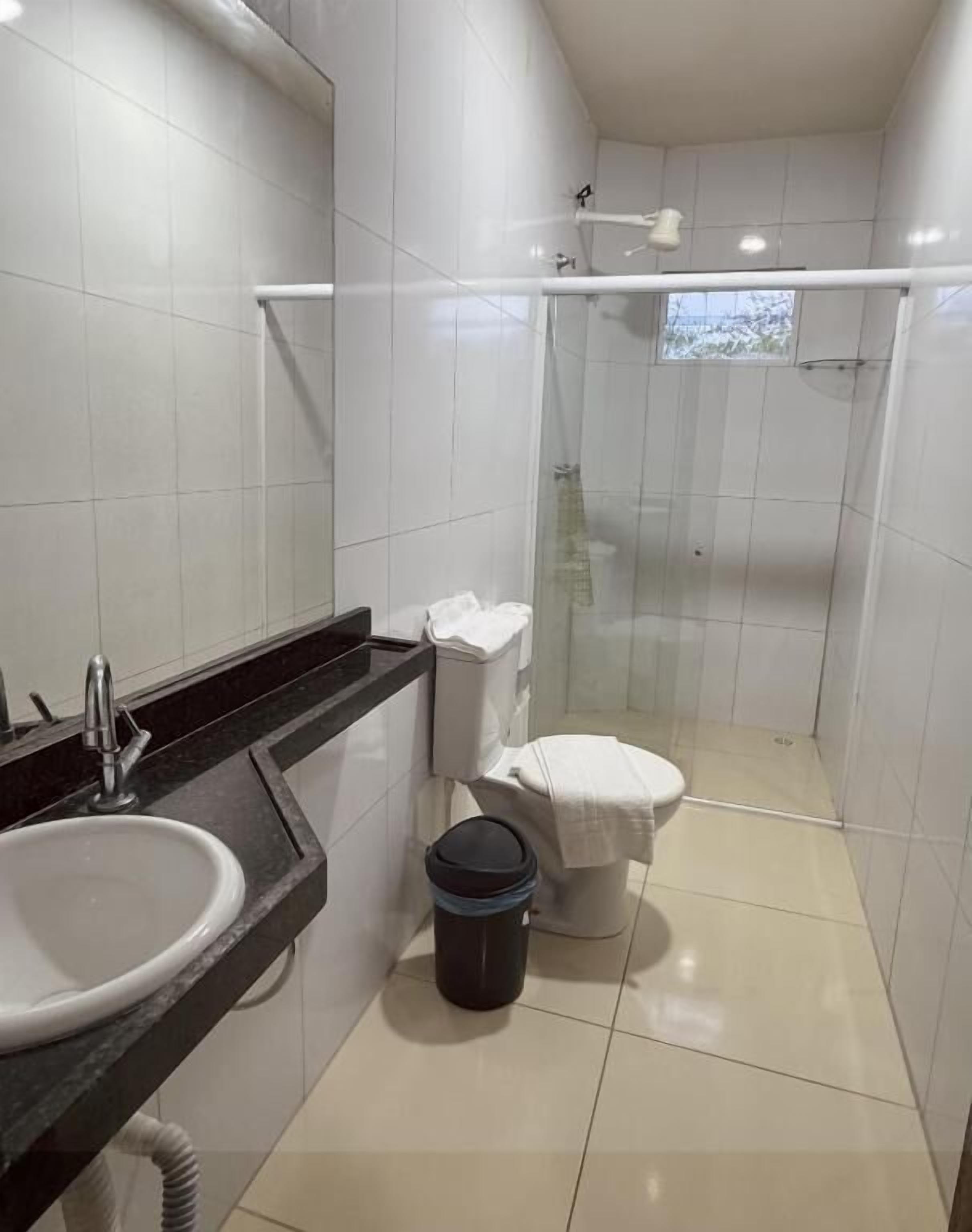 A small, modern bathroom with a white sink, toilet, and shower.