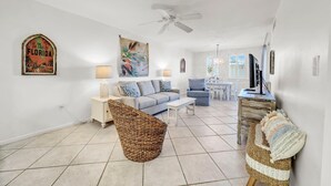 A spacious living area with a sofa, a coffee table, a TV, and a ceiling fan. - Jetty East 106b (Destin)