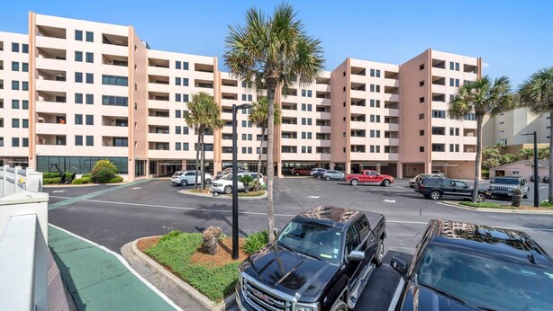 A multi-story hotel with a parking lot in front. - Jetty East 106b (Destin)