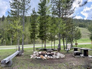A campsite with a fire pit, benches, and a table.