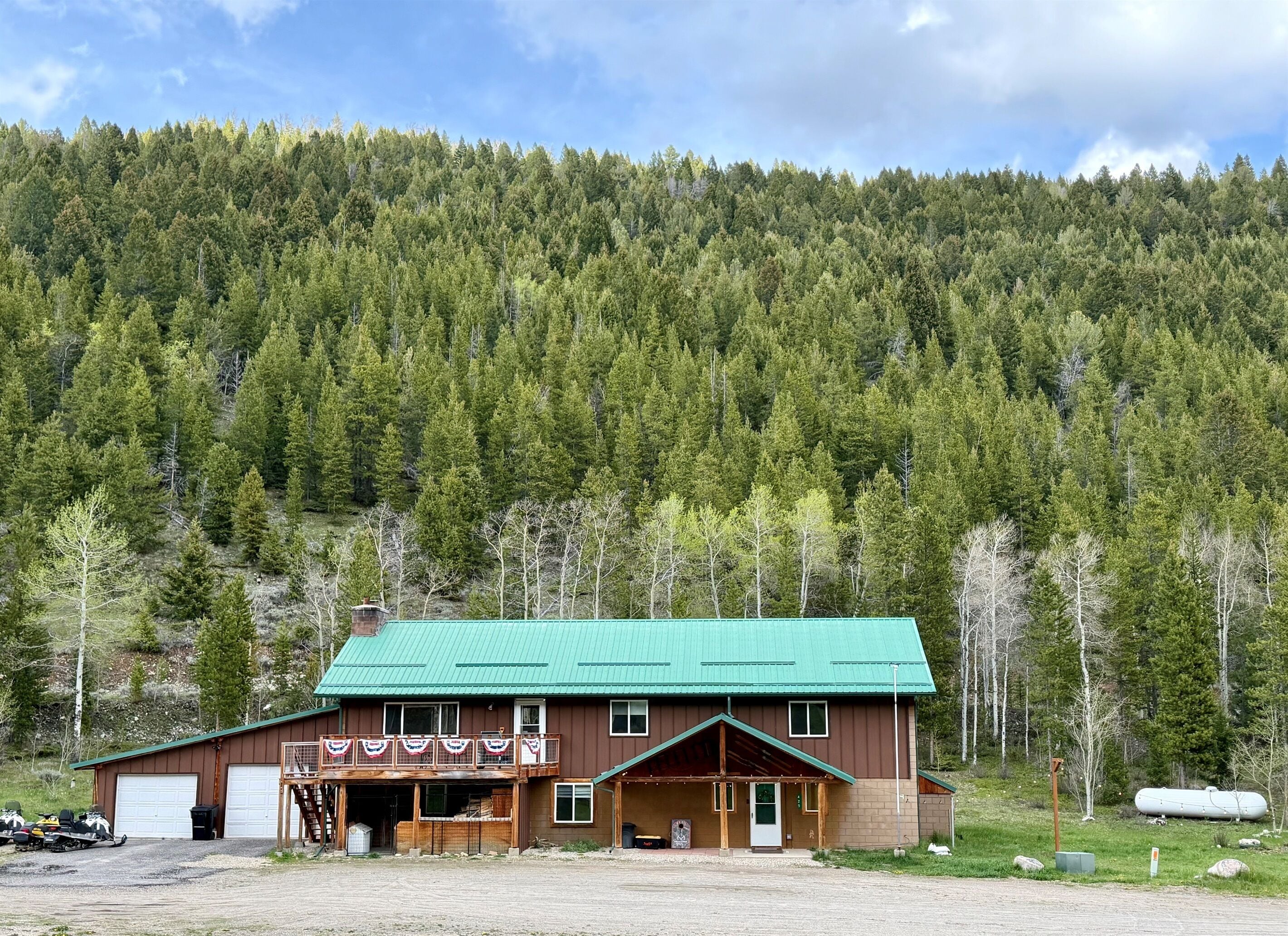 A two-story building with a green roof, a covered porch, and a garage.