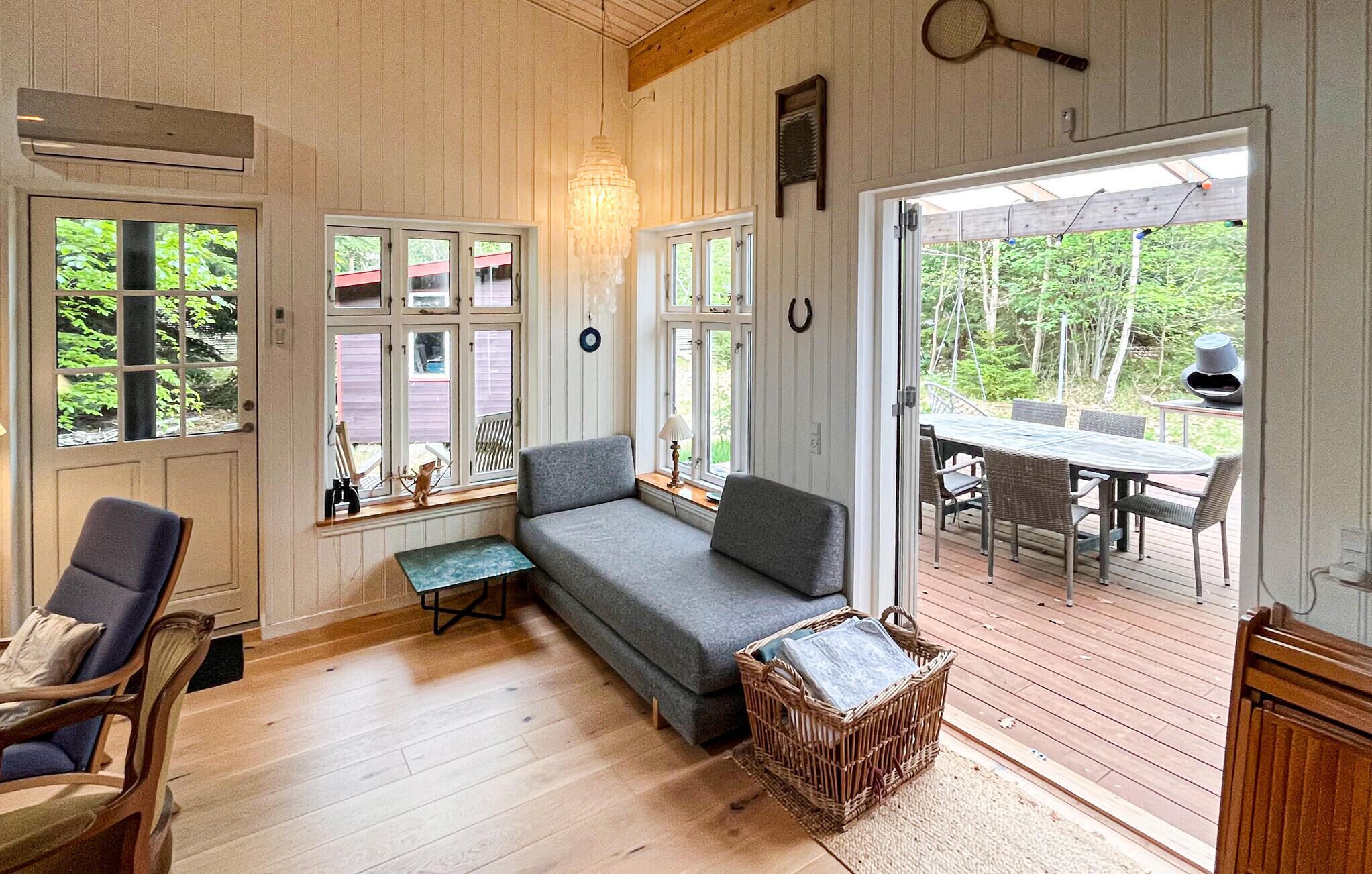 Une pièce chaleureuse avec un canapé gris, une chaise en bois, une petite table et un panier en osier.