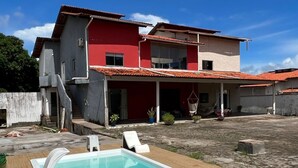 Une maison à deux étages dotée d’une piscine, d’un patio couvert et d’une façade rouge et blanche.