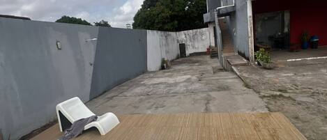A rooftop with a swimming pool, a red building, and a grey wall.
