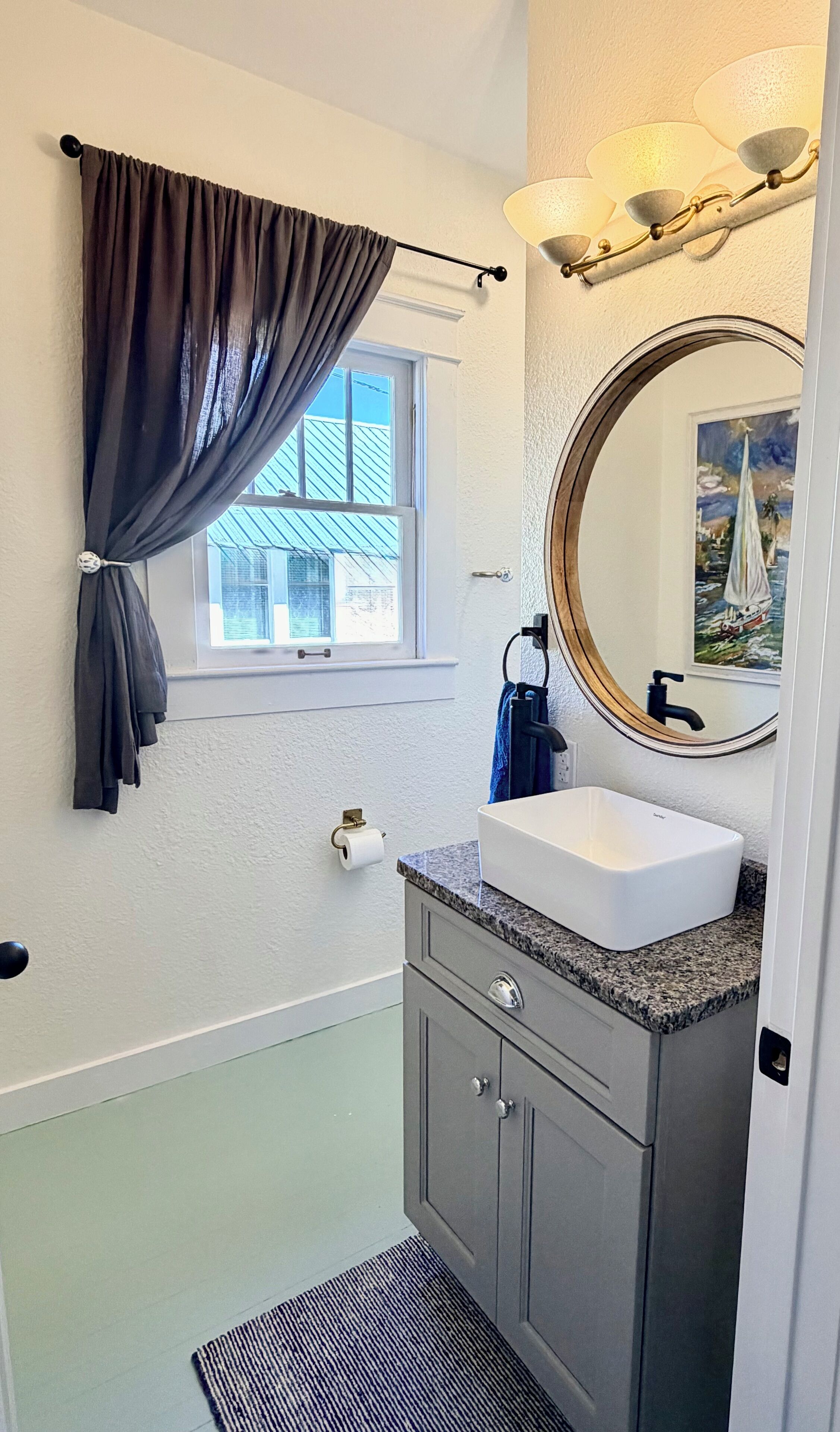 Une salle de bain avec une fenêtre, un lavabo, un miroir et un porte-serviettes.
