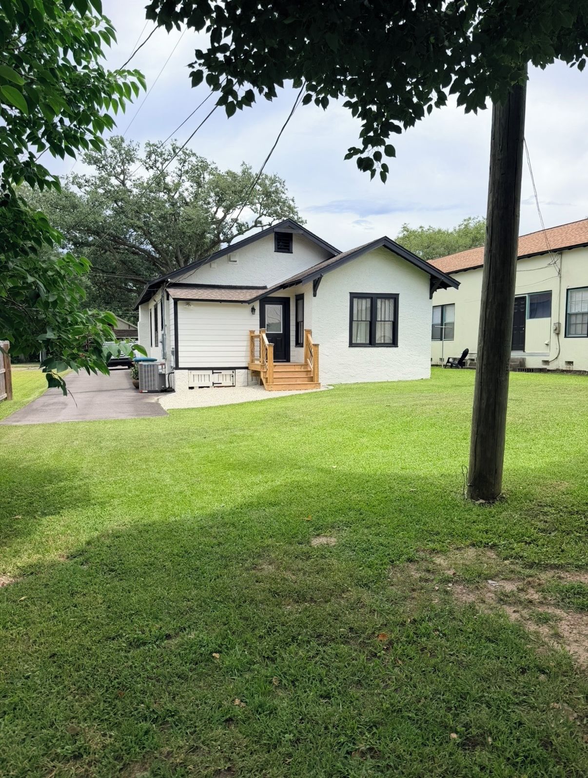 Ein Bungalow mit einer Veranda und einer kleinen angeschlossenen Garage.