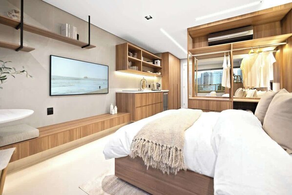 Une chambre moderne avec un grand lit, une coiffeuse intégrée, une télévision et une armoire avec un miroir.