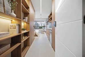 Un couloir d’hôtel moderne, avec des étagères en bois, un lit et une vue sur la ville.