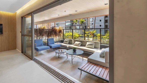 Una sala de estar moderna con pared de vidrio, un juego de sofá, una mesa de centro y un sillón azul.