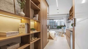 Un interior moderno con estanterías de madera, una cama y vistas a edificios.