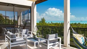 Ein Balkon mit Gartenmöbeln, einer Hängematte und Blick aufs Meer.