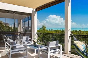 A balcony with outdoor furniture, a hammock, and a view of the ocean. - Bora Villa 2 BR (Long Bay)