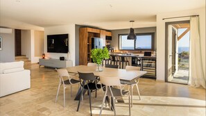 Un salon moderne comprenant un coin repas, une cuisine et une grande fenêtre offrant une vue dégagée.