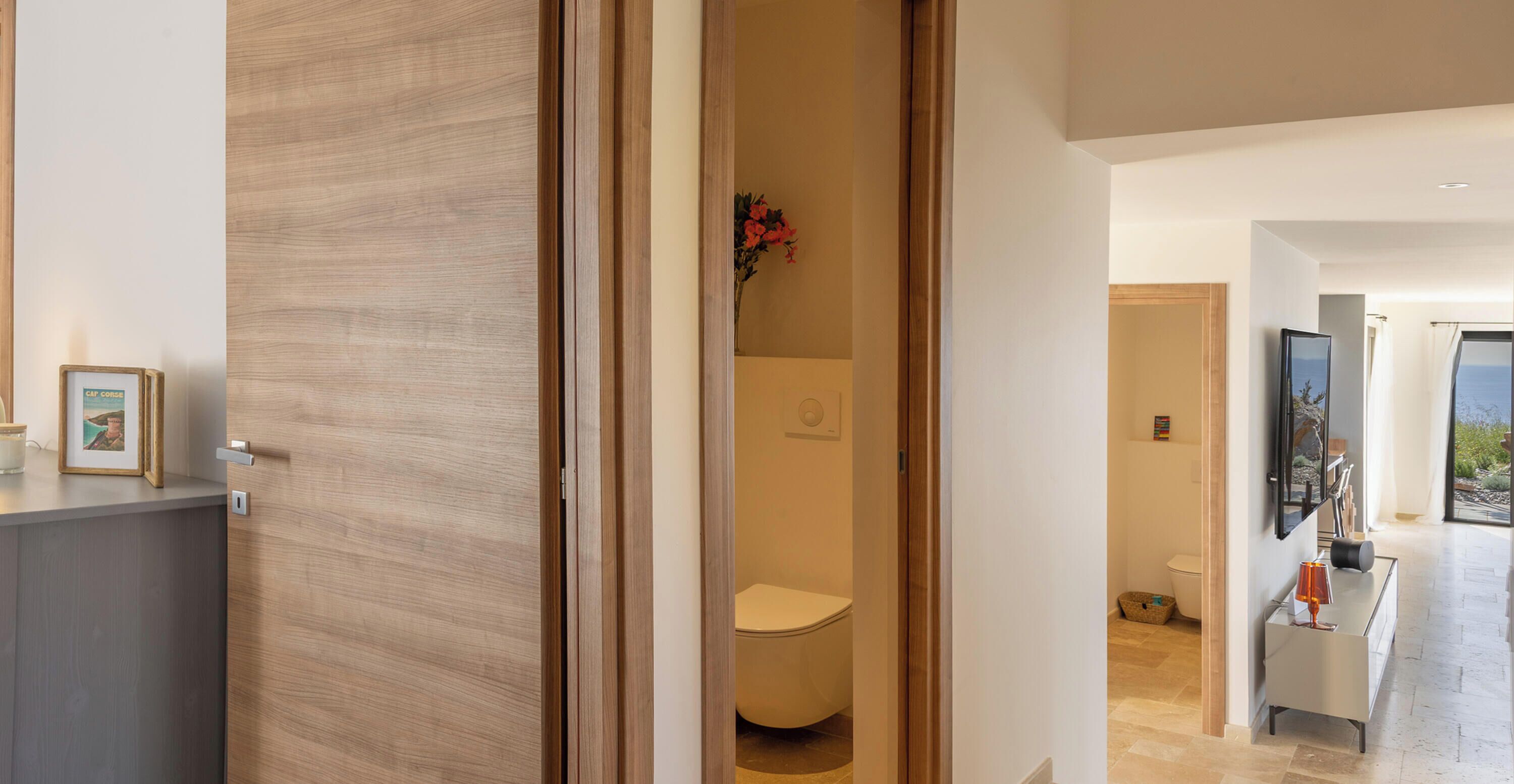 A modern bathroom with a toilet, a shower area, and a vanity with a mirror and a lamp.