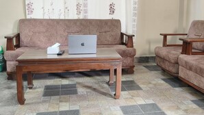 Un salon avec un canapé, des fauteuils, une table basse et un ordinateur portable.