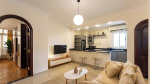 A modern living room with a beige sofa, a small white table, and a TV.