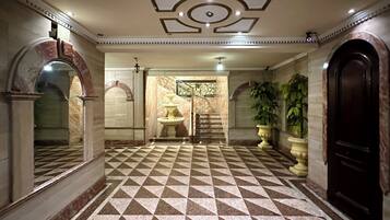 A lobby with a checkered floor, a fountain, and a staircase leading to another area.
