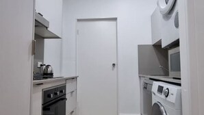 Kompakti keittiö, jossa on sisäänrakennettu uuni, mikroaaltouuni ja pesukone.