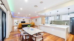 Une cuisine moderne avec des meubles blancs, un îlot central et des luminaires suspendus.