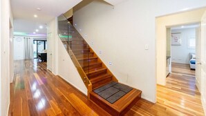 Un escalier moderne avec des rampes en verre et des marches en bois menant à un palier situé au deuxième étage.