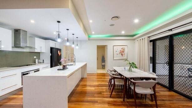 Une cuisine moderne dotée d’un îlot central, de planchers en bois et de luminaires suspendus.