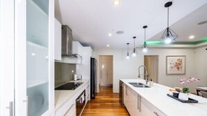 Une cuisine moderne avec des armoires blanches, un plancher en bois et des luminaires suspendus.