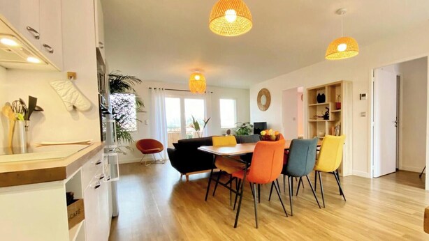 Una cocina moderna con comedor, suelo de madera e iluminación colgante.