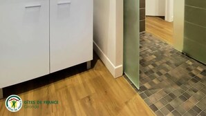 Un baño moderno con un espejo grande, muebles blancos y una zona de ducha con puerta de cristal.