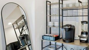 A modern kitchen with a coffee bar, a coffee maker, and a blender.
