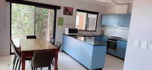 A modern kitchen with a dining area, featuring a large island, blue cabinets, and a microwave.