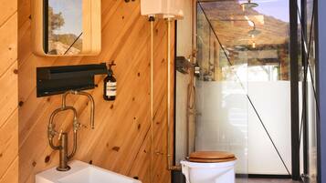 Un baño de madera con lavamanos blanco, inodoro y ducha.
