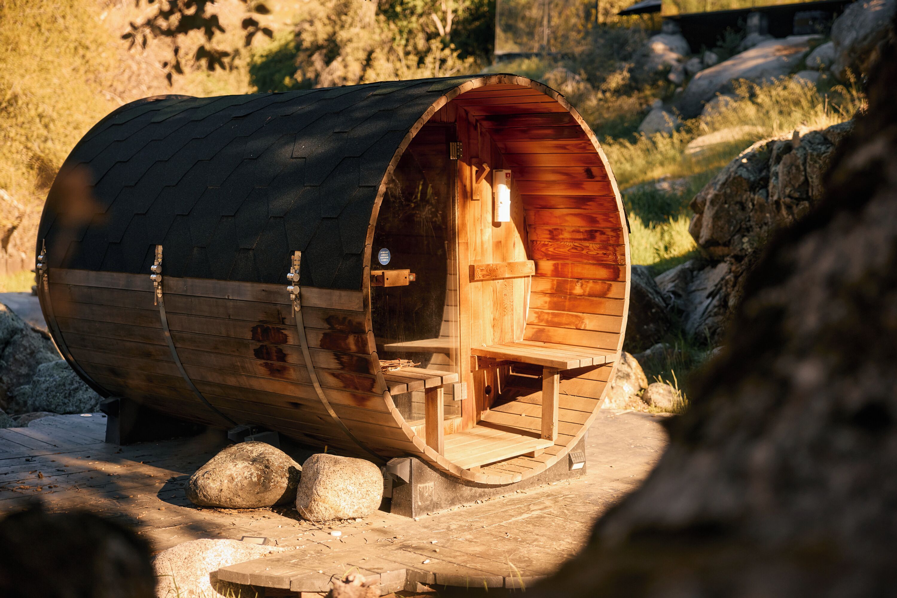 Una estructura en forma de barril de madera, con un muelle de madera y un banco.