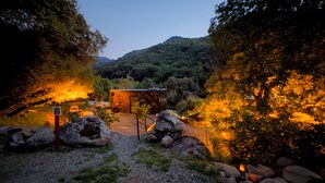 Un rustico chalet con un sentiero in pietra che vi conduce, circondato da alberi e con una montagna sullo sfondo.