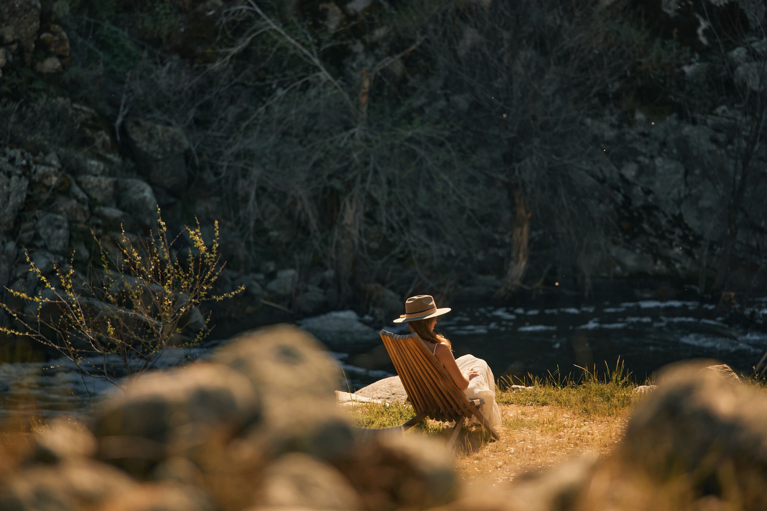 A person sitting on a chair facing a rocky landscape with sparse vegetation.