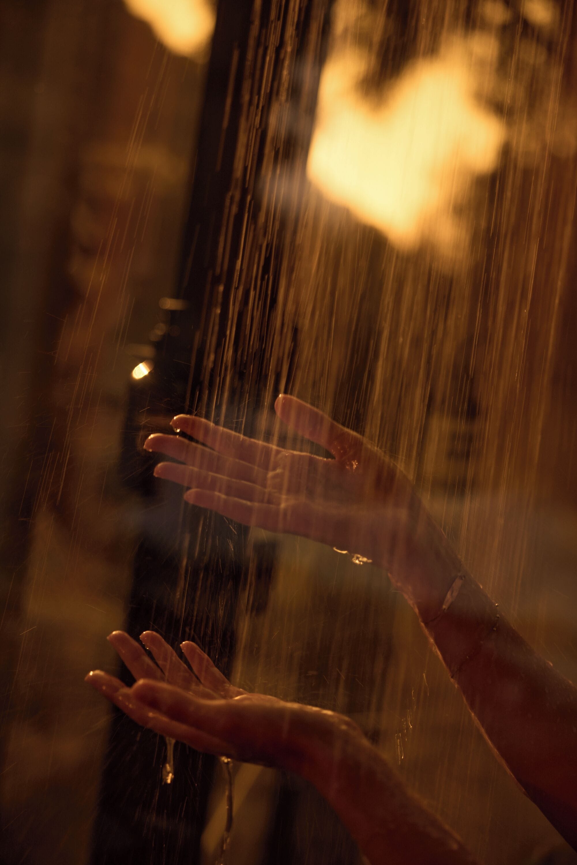 A hand reaching out towards falling rain.