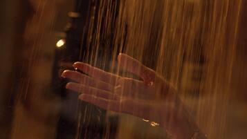 A hand reaching out towards falling rain.
