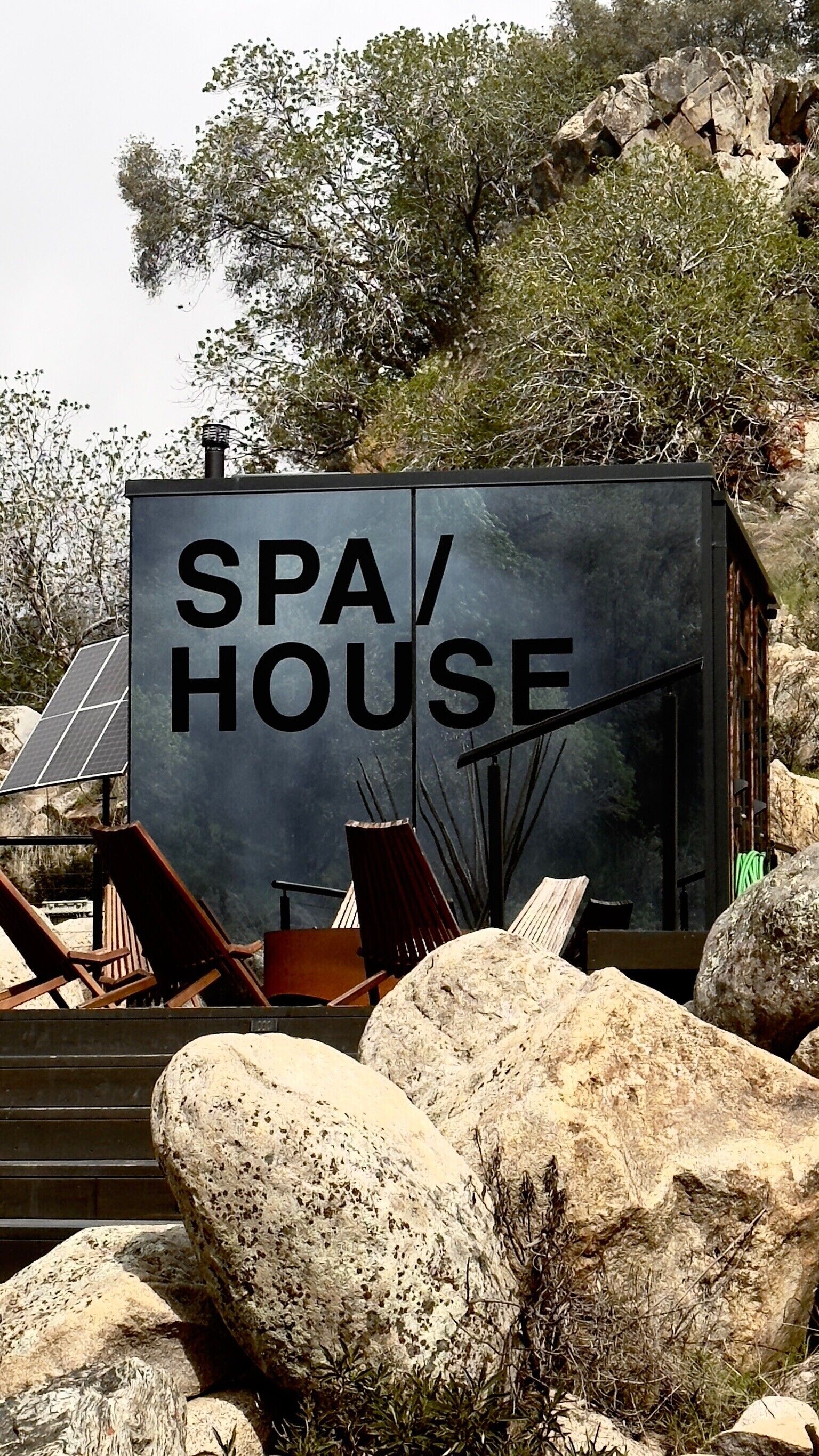 A spa house with a sign, surrounded by rocks and trees.