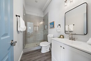 Un bagno moderno con doccia vetrata, un water bianco e un grande specchio sopra il lavandino.