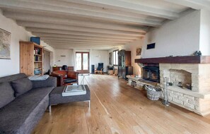 A spacious living room with wooden flooring, a fireplace, a sofa, and a bookshelf. - Charmant avec vue paysagère (Castels et Bézenac)