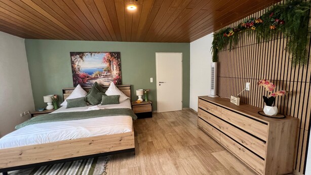 Un dormitorio con una cama de madera, un aparador, un cuadro y una decoración en la pared.
