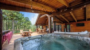 Une cabane en bois dotée d’un bain à remous, d’un espace extérieur aménagé et offrant une vue sur la forêt.