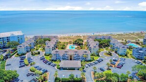 Un complexe hôtelier comprenant plusieurs bâtiments, une piscine centrale et offrant une vue sur la plage.