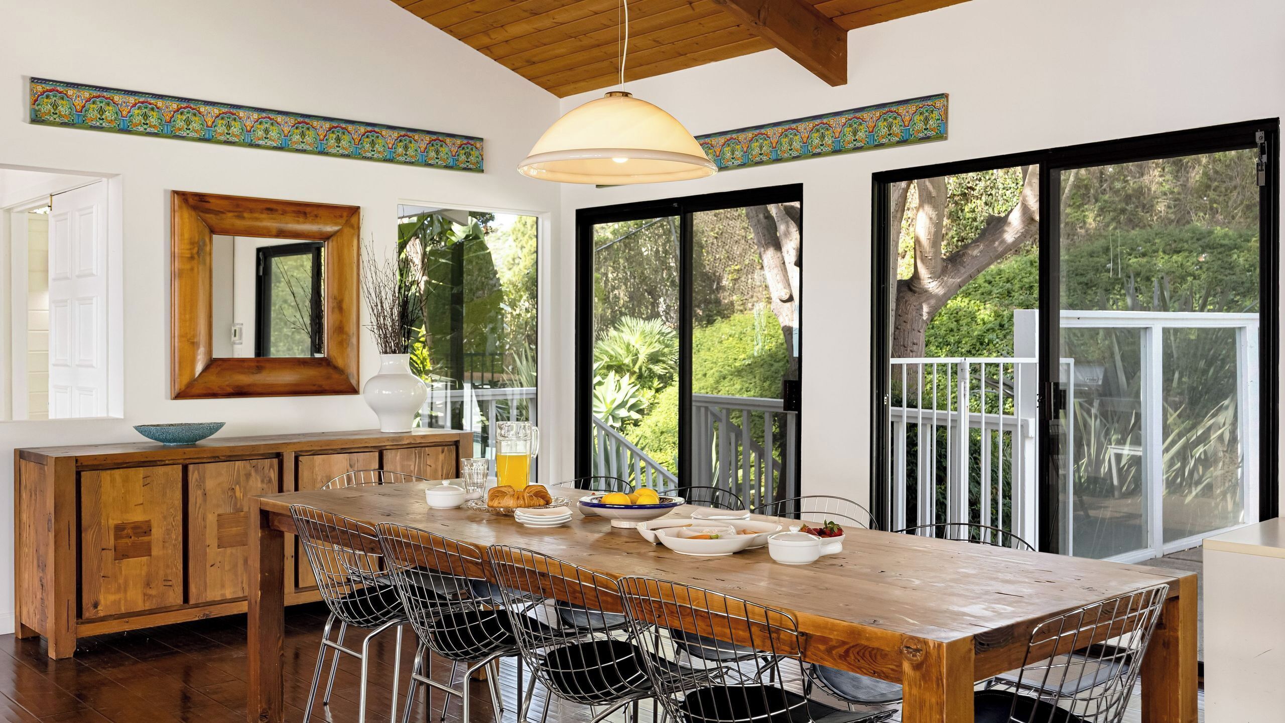 Una cocina moderna con una mesa de madera, sillas de metal y ventanas amplias.